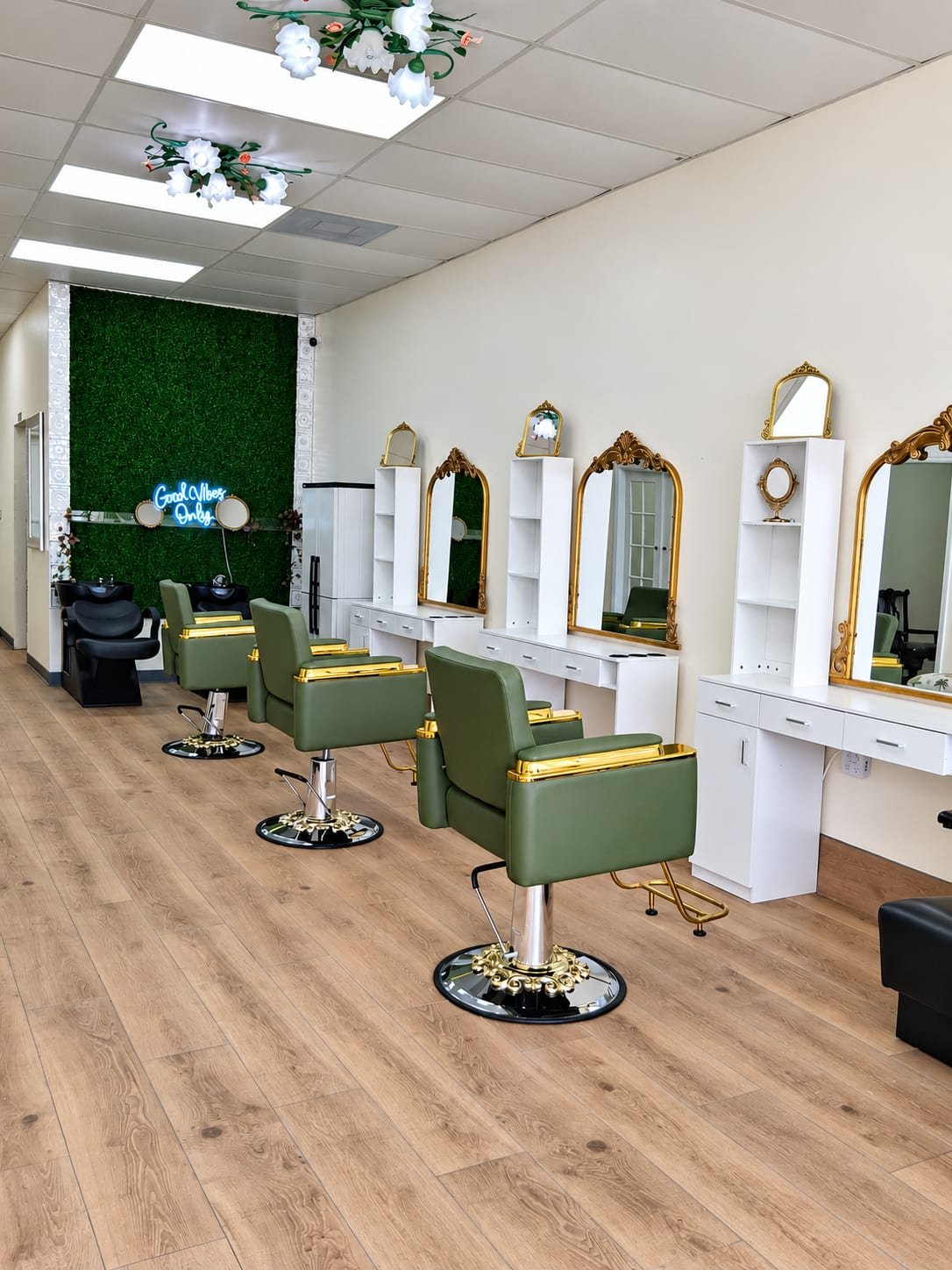 Styling stations with sage and gold chairs and a moss wall with a Good Vibes Only neon